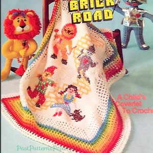 May include: A crochet baby blanket pattern featuring characters from the Wizard of Oz. The pattern includes Dorothy, the Scarecrow, the Tin Man, the Cowardly Lion, and Toto. The blanket has a rainbow border.