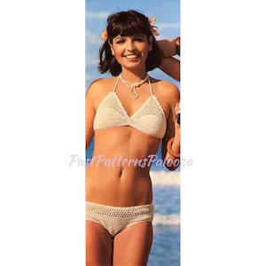May include: A white crocheted bikini top and bottom. The top has a halter style with a white beaded necklace. The bottom is a high-waisted style.