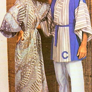 May include: A woman wearing a silver and white patterned robe with a blue and white striped robe with a blue "C" on the front.