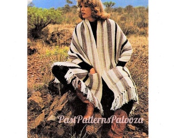 May include: A crocheted striped shawl in white, brown, and black with fringe. The shawl is draped over a person sitting on a rock in a desert landscape.