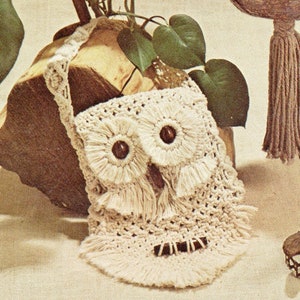 Peut inclure: Un sac en crochet en forme de hibou avec une longue bandoulière. Le sac est fait de fil de couleur crème et a des yeux en boutons marrons. Le sac a une frange autour du bas.