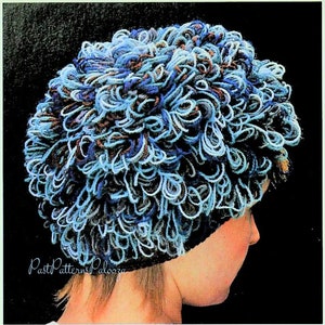 May include: A blue, brown and white crocheted hat with a curly texture. The hat is being worn by a person with short, brown hair.