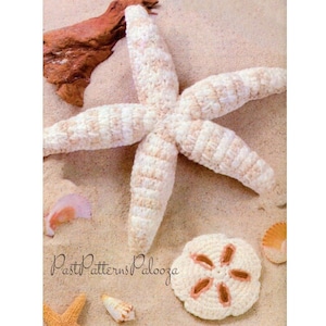Puede incluir: Una estrella de mar y un dólar de arena tejidos a crochet sobre un fondo arenoso. La estrella de mar es blanca con rayas beige y el dólar de arena es blanco con detalles beige. El texto "Past Patterns Palooza" es visible en la esquina inferior izquierda de la imagen.