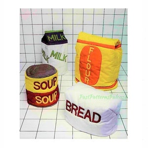 Puede incluir: Cuatro alimentos de tela para jugar: una bolsa de "Harina" amarilla y naranja, un cartón de "Leche" blanco y verde, una lata de "Sopa" amarilla y roja y una hogaza de "Pan" blanca. Los artículos están sobre un fondo a cuadros blanco y negro.