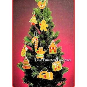 May include: A collection of felt Christmas ornaments hanging on a green tree, including a gingerbread person, a candy cane, a house, a bell, a drum, a stocking, a bird, and a horn, all featuring white stitching and small red bead accents.