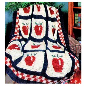 May include: A crocheted blanket with a red, white, and blue apple design. The blanket is made with a checkered border.