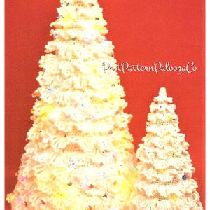 May include: Two crocheted Christmas trees, one large and one small, are decorated with white and colorful beads. The trees are on a red background.