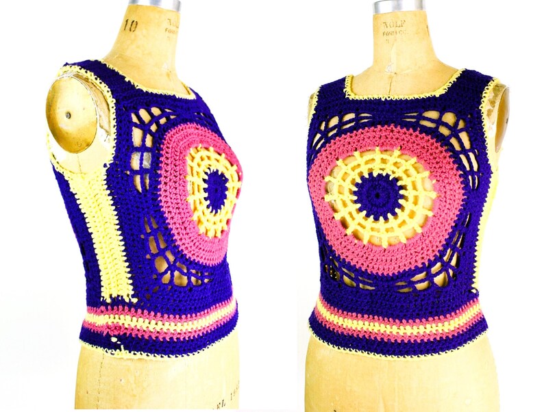 Op de afbeelding: Een gehaakt topje zonder mouwen met een cirkelvormig ontwerp in tinten paars, roze en geel. Het topje heeft een brede, open halslijn en een aansluitende pasvorm.