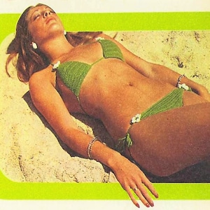 May include: A green crochet bikini with white flower accents. The bikini top is a triangle style, and the bottoms are a low-rise design. The image is set against a sandy background, with a bright green border.