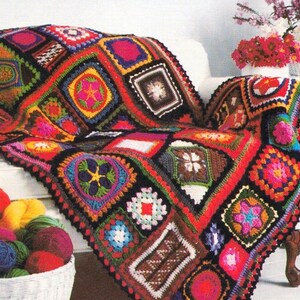 May include: A colorful crocheted throw blanket with a patchwork design featuring various geometric shapes and floral motifs. The blanket is draped over a white couch and is made with a variety of bright colors, including red, orange, yellow, green, blue, and purple.