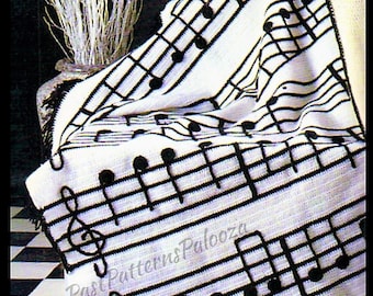 May include: A white and black crocheted blanket featuring a musical staff and notes design. The blanket has a black fringe and the text "Past Patterns Palooza" is visible. The blanket is draped over a chair.
