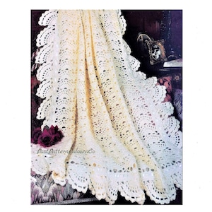 May include: A white crocheted blanket with a scalloped edge. The blanket is draped over a chair with a floral pattern.