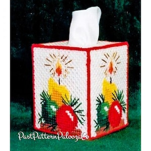 Peut inclure: Un couvre-boîte à mouchoirs en plastique blanc sur le thème de Noël. Le couvercle présente un motif rouge, vert et jaune avec des bougies et des ornements. Le texte "PastPatternPaloozaCo" est visible en bas de l'image.