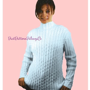以下が含まれることがあります： モックネックとジッパーが付いた、ライトブルーのケーブルニットセーター。セーターはテクスチャード加工のパターンと長袖です。「Past Pattern Palooza Co」の文字が左下にあります。背景は無地のピンクです。