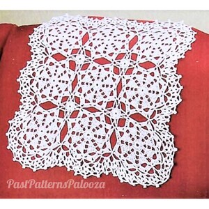 May include: White crocheted doily with a delicate floral pattern. The doily is square shaped and has a scalloped edge. It is displayed on a red background.