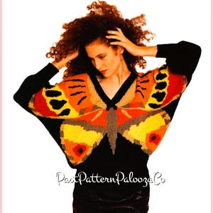 May include: A black sweater with a large butterfly design in shades of orange, yellow, and brown. The butterfly wings span the shoulders and chest. The text "PatPatternPaloozaCo" is at the bottom.