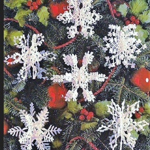 May include: Five white crocheted snowflakes hanging on a green Christmas tree branch with red berries and ornaments.
