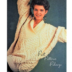 May include: A close-up of a woman wearing a white knitted jumper with a cable knit pattern. The jumper has a shawl collar and is worn over a white shirt. The woman has short brown hair and is smiling. The text "Past Patterns Palooza" is visible in the bottom right corner of the image.