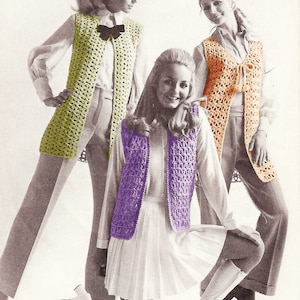 May include: Three women wearing crocheted vests in different colors: green, orange, and purple. The vests are long and have a tie at the neck.