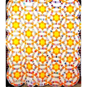 May include: A quilt with a pattern of interlocking circles and stars. The circles are made of colorful fabric scraps and the stars are yellow. The quilt is edged in a white fabric.