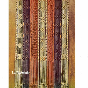 May include: A macrame wall hanging with a geometric pattern in shades of brown, orange, and beige. The hanging is made of knotted cords and features wooden beads.