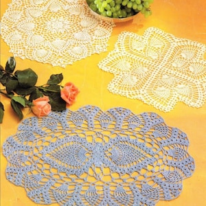 Może przedstawiać: Trzy koronkowe serwetki w różnych rozmiarach i kształtach. Serwetki są białe i jasnoniebieskie. Serwetki leżą na żółtym tle.