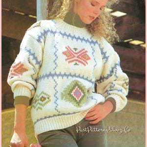 May include: Cream-colored knit sweater with geometric patterns in pink, green, and blue. The sweater has long sleeves and a crew neck. The image also shows olive green pants and a pair of boots.