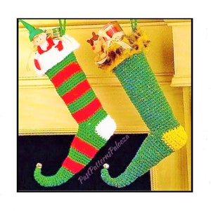 May include: Two green and yellow crocheted elf stockings with red and white stripes hanging on a fireplace mantel. One stocking has a small elf doll inside and the other has a small reindeer doll inside.