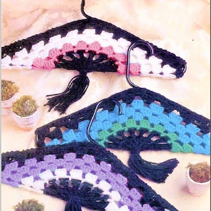 May include: Three crocheted hangers in black, white, pink, blue, green, and purple. Each hanger has a black tassel.