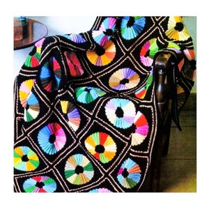 May include: A colorful crocheted throw blanket with a black background and circular patterns in various colors. The blanket is draped over a wooden chair.