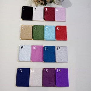May include: A collection of sixteen small, square velvet-covered boxes in various colors, including black, white, red, pink, gold, green, blue, and purple. Each box has gold corner protectors. The boxes are arranged on a white surface.