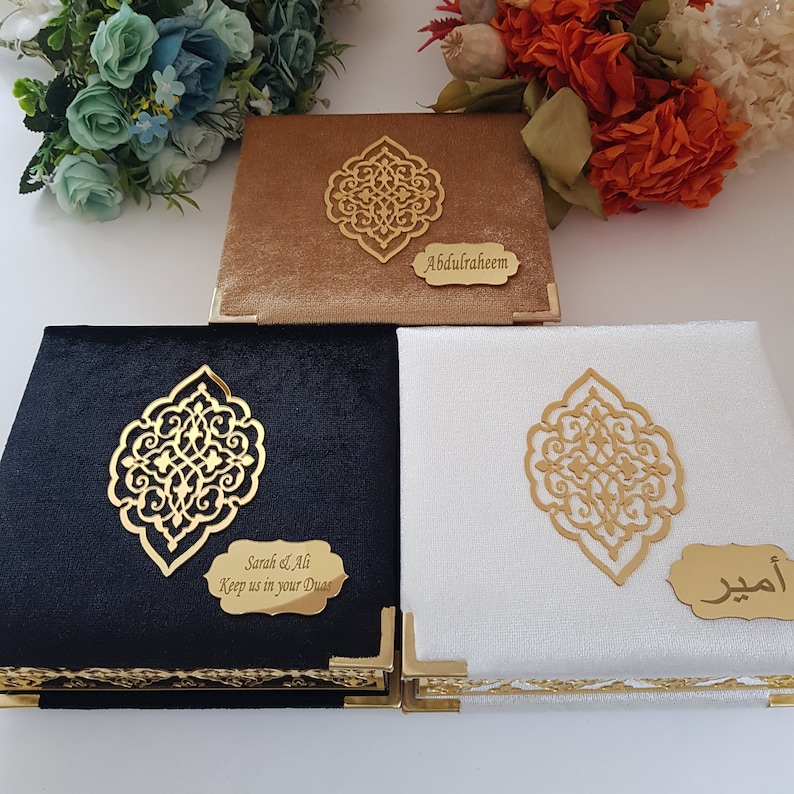 May include: Three decorative boxes with gold trim and intricate designs. The boxes are covered in velvet fabric in black, white, and brown. Each box has a personalized inscription: "Sarah & Ali Keep us in your Duas", "Abdulraheem", and "أحمد".