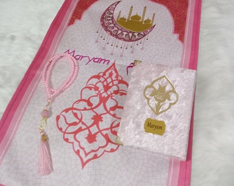 Peut inclure: Tapis de prière rose avec un croissant de lune doré et un motif de mosquée. Le tapis a une frange blanche et le nom "Maryam" est écrit dessus. Un livre de prière rose avec le nom "Maryam" est également inclus.