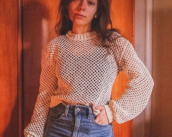 May include: A white crochet sweater with a loose fit and long sleeves. The sweater has a large, open-weave pattern.