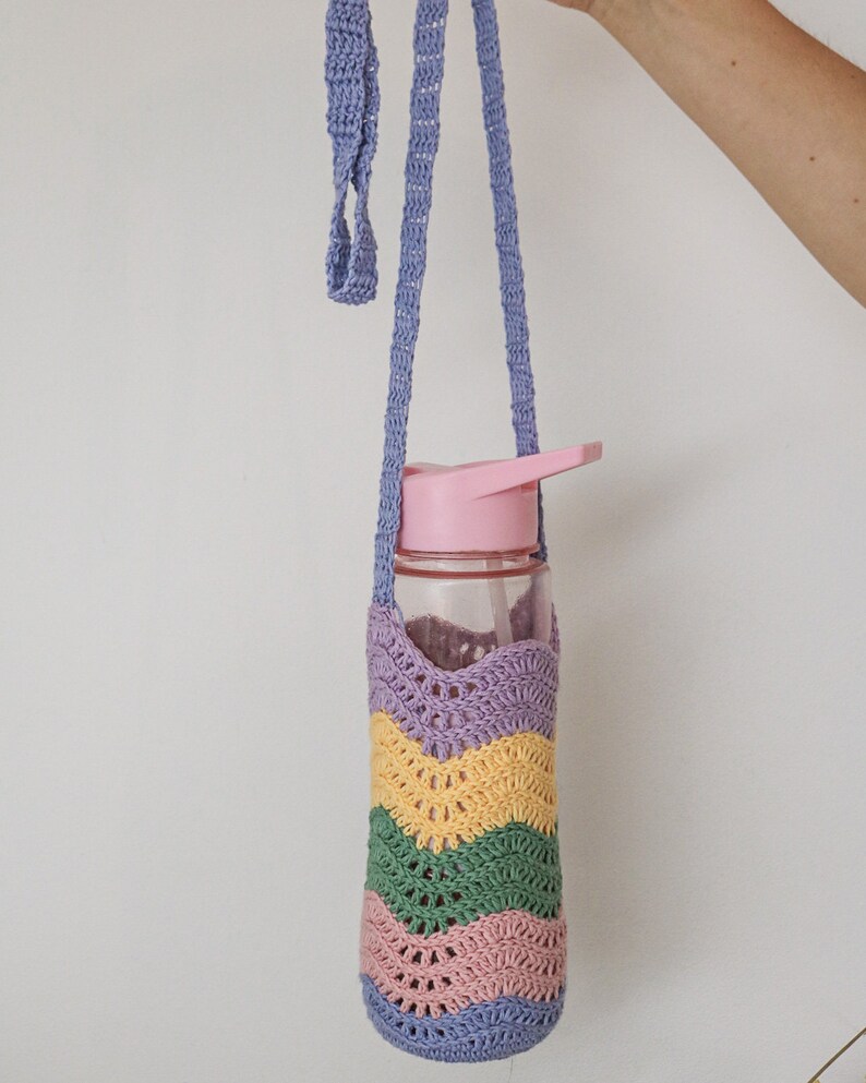 A crocheted water bottle holder with a purple, yellow, green, and pink striped pattern. The holder has a long purple strap.