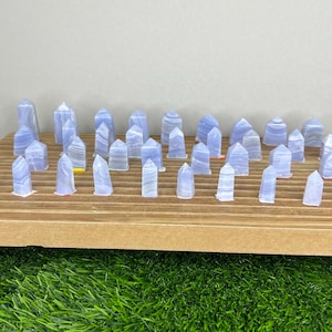 May include: A collection of blue lace agate points arranged on a wooden surface. The points are various sizes and shapes, with some having a more pronounced banding pattern than others.