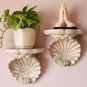 May include: A white ceramic mug with a black handle and the text "But First, Coffee" in a bold, black font. The mug is set against a neutral background, highlighting its simple design.