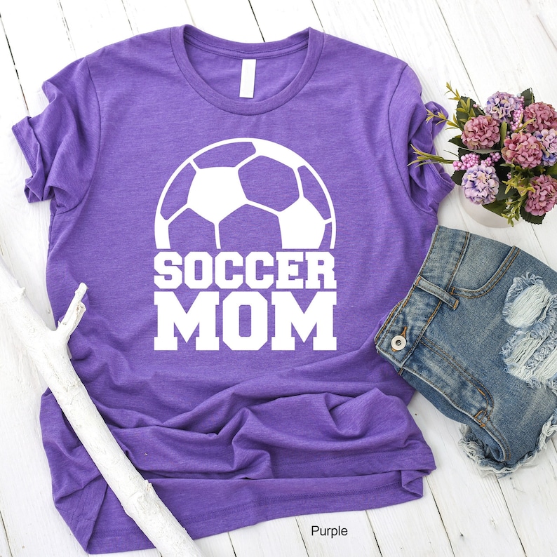 May include: Purple t-shirt with a white soccer ball and the text "SOCCER MOM" printed on it.