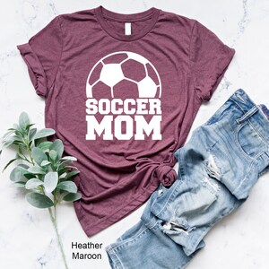 May include: Heather maroon t-shirt with a white soccer ball and the text "SOCCER MOM" printed on the front.