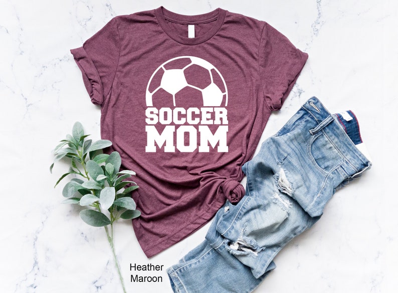 May include: Heather maroon t-shirt with a white soccer ball and the text "SOCCER MOM" printed on the front.