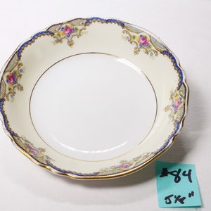Może przedstawiać: Biała porcelana miska z niebieskim i złotym wzorem kwiatowym. Miska ma średnicę 14 cm.