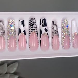 May include: Set of ten long, pink and white press-on nails with different animal print designs. Some nails have rhinestones.