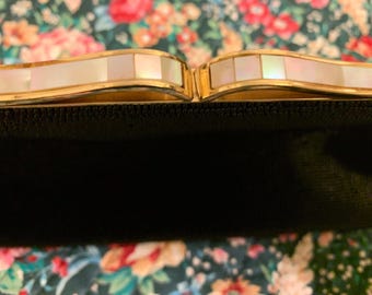 May include: A black clutch bag with a gold metal frame and a white mother-of-pearl inlay.