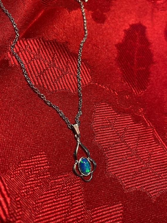A silver tone chain with small faux opal pendant.