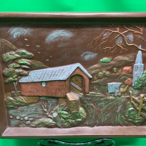 A Holland Mold from 1972, of a covered bridge, horse and buggy and church steeple in the background.