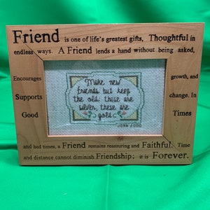 May include: A wooden frame with a cross-stitch design inside. The frame has a quote about friendship that reads: "Friend is one of life's greatest gifts, Thoughtful in endless ways. A Friend lends a hand without being asked, Encourages Supports Good Make new friends but keep the old those are silver, these are gold growth, and change. In Times and bad times, a Friend remains reassuring and Faithful. Time and distance cannot diminish Friendship; it is Forever."