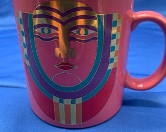 A famous Laurel Burch coffee mug with Māori face mask.