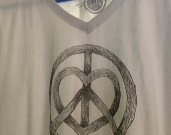 May include: A white V-neck t-shirt featuring a black hand-drawn style graphic of a peace sign combined with a heart shape in the centre. The text "LIFE IS GOOD" is printed in small black letters below the graphic, and the inner label indicates size M.