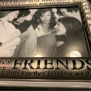 May include: A silver-toned picture frame with a black and white photo of four friends. The frame has an inscription that reads "Friends are the best buds, sort of trust and advice, friends giggle, smile, long talks, friends laugh, times friends are the best BFF, time together brighten my day friends". The frame measures 4 inches by 6 inches.