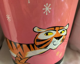 May include: Pink metal trash can with a cartoon tiger and white snowflakes. The tiger has orange and black stripes and yellow eyes.